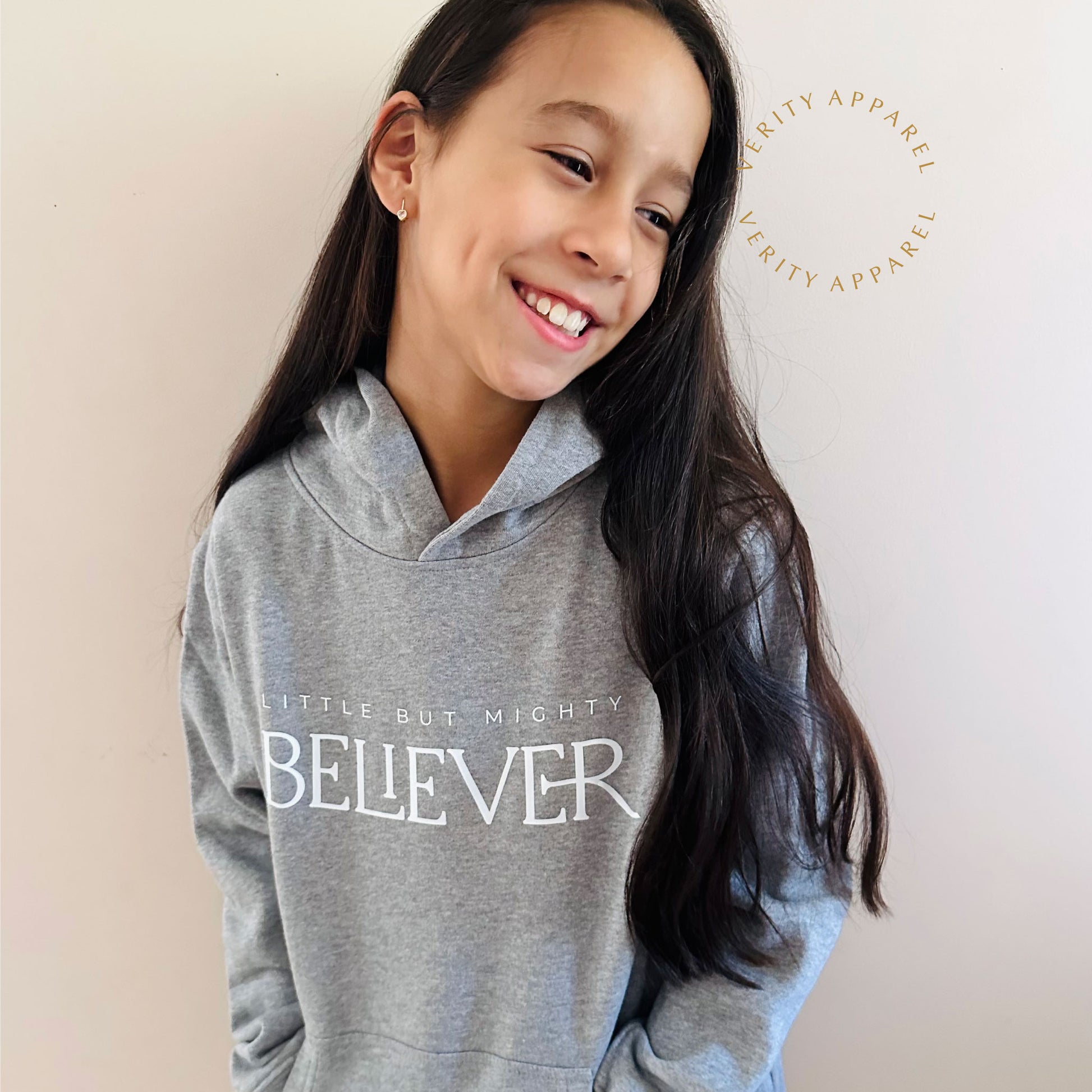 Comfy kids faith hoodie styled for winter. Young girl wearing soft grey Christian hoodie with "Believer" print on it.