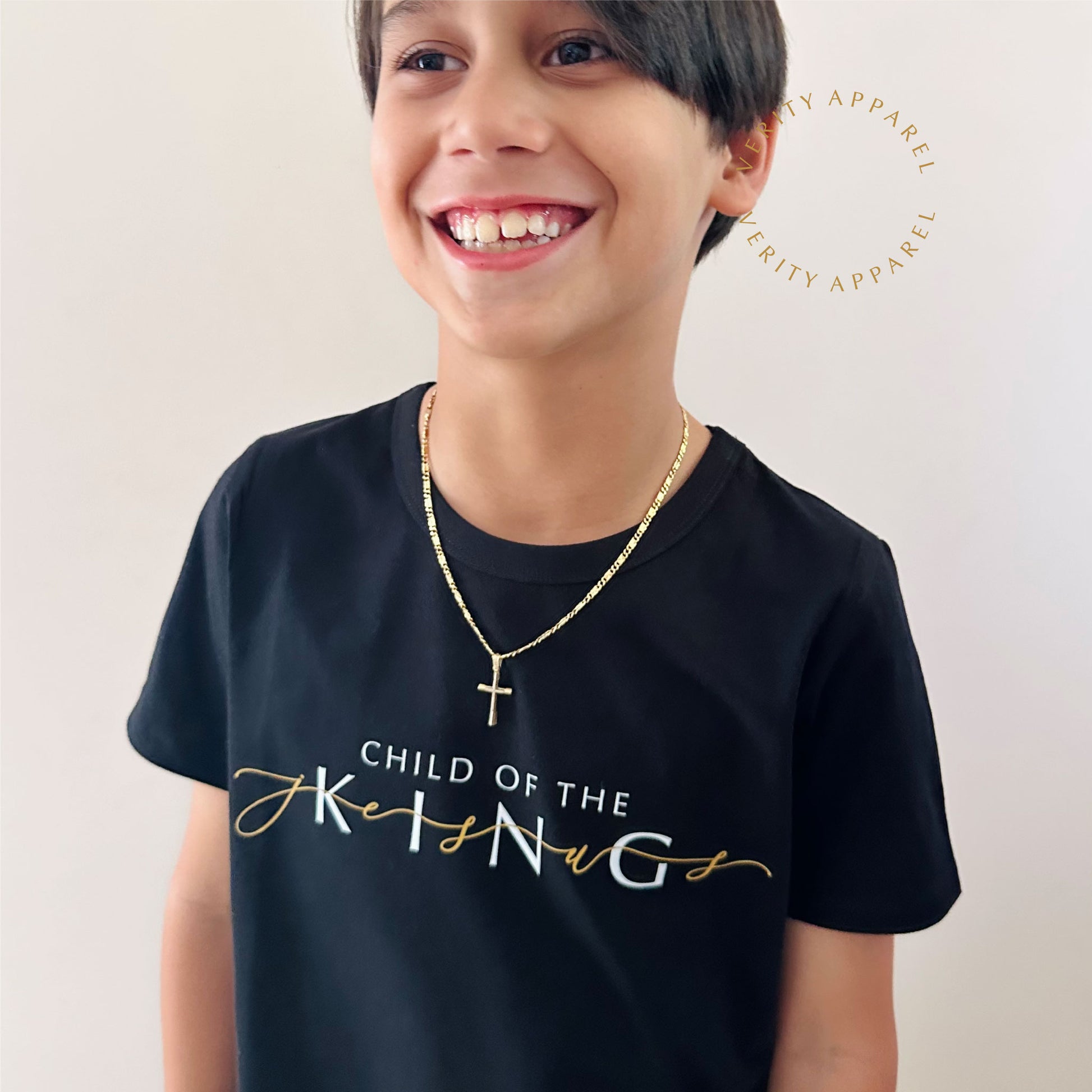 Young boy wearing 'Child of the King' christian kids tee in black cotton. The design features the word Jesus in gold weaved through the design.