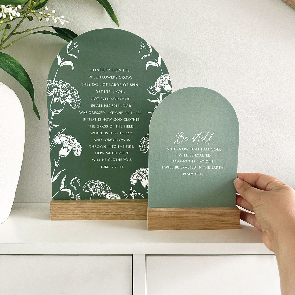 Wildflowers and Be Still Verse & Oak scripture stands with a hand holding the smaller Be Still stand