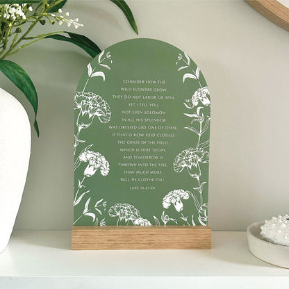 Wildflowers Luke 12:27–28 Verse & Oak stand - features the bible scripture with white floral illustrations against grass green with a handcrafted Tasmanian oak base. Styled on a white shelf with decorative vase and coral.