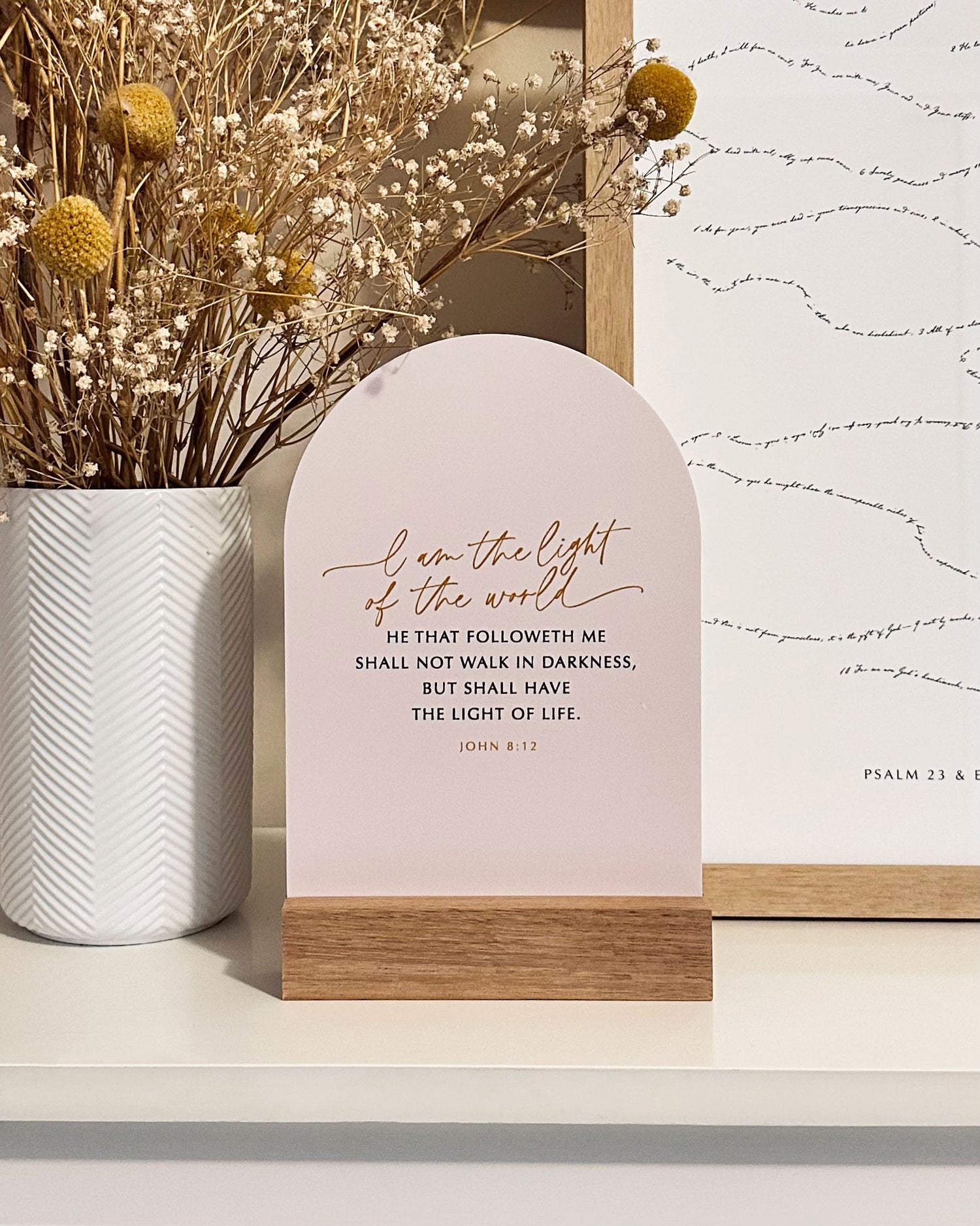 Light Verse & Oak scripture stand displaying John 8:12 on a timber base, styled on a white shelf with dried florals — Verity The Label Australia.